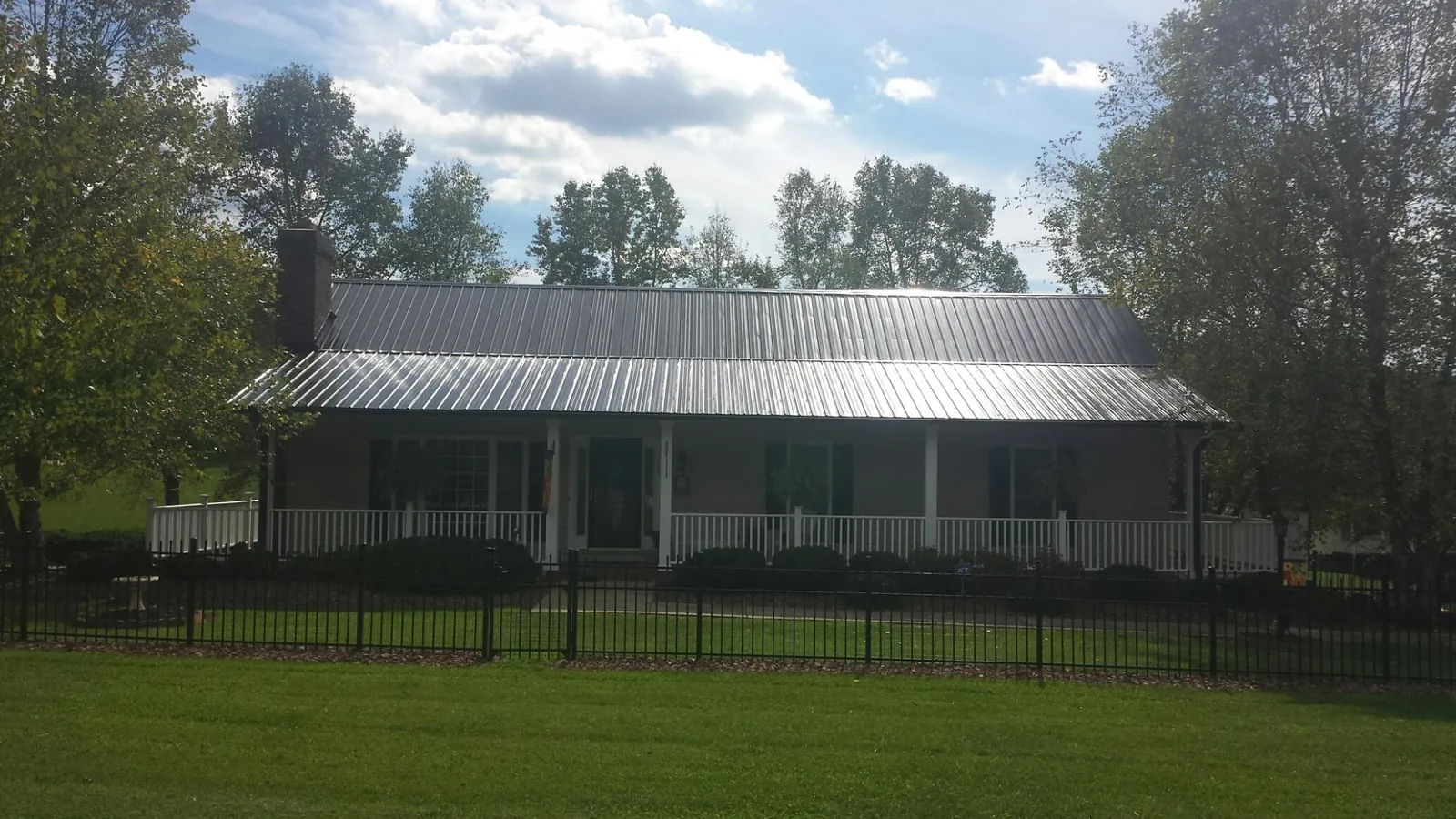 Gray metal roof on a brick ranch with a full width front porch — Gutter Guard Installation work by our crew in Woodland